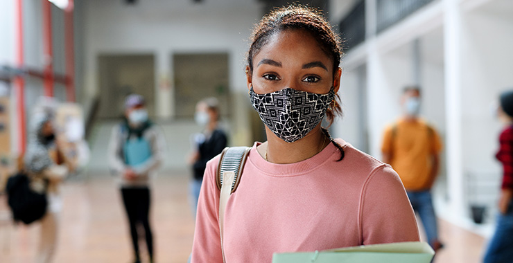 Female student wearing a face mask and holding a binder