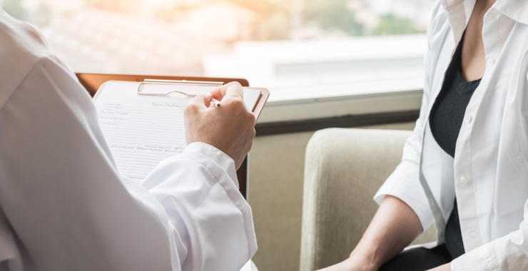 A health care professional reviews paperwork with a patient during a women’s health consultation.