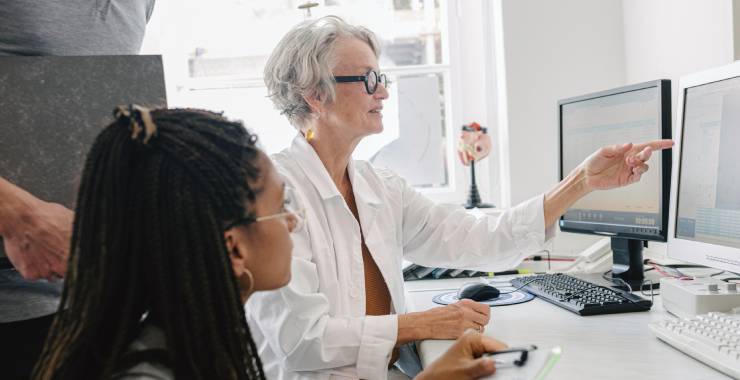 Medical professionals in an office reviewing information on computer screens.