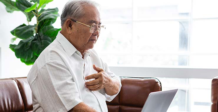 An older man sitting on a couch with a laptop