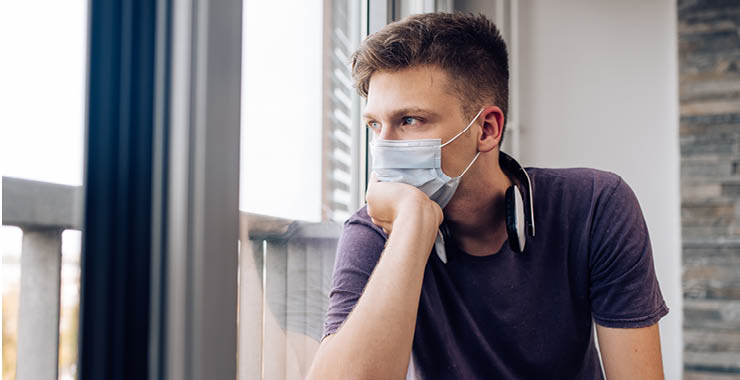 Man wearing face mask looking out the window