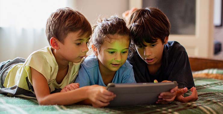 Three kids looking at a tablet