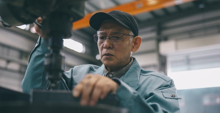 A factory worker operates industrial equipment inside a manufacturing facility.