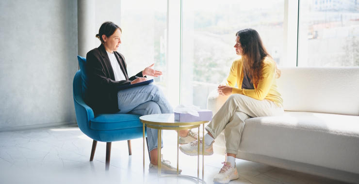 A psychologist and an individual sit across from each other in an office, engaged in conversation.