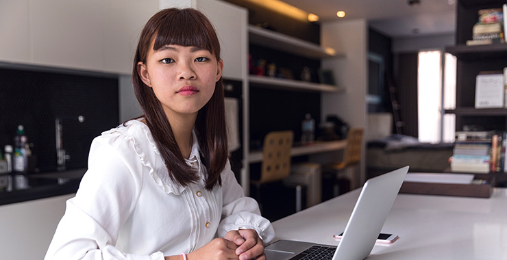 Asian woman sitting at a desk with a laptop