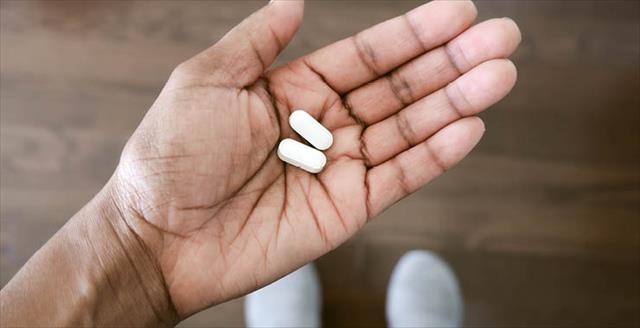 Hand holding two pills