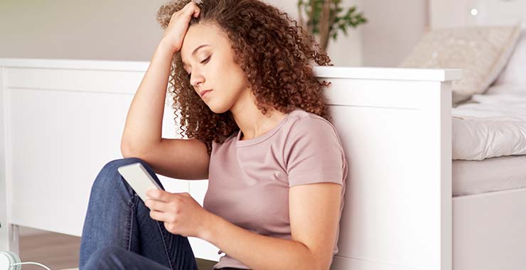 Teenage girl staring at cell phone screen