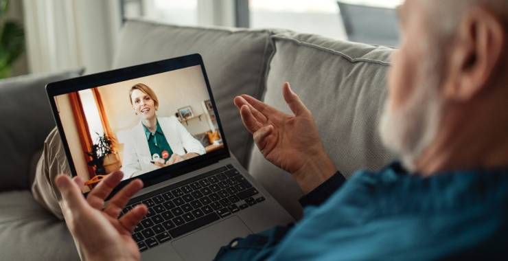 Senior man sitting on sofa and having video call with his doctor