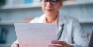 Healthcare professional reviews a document in a clinical office setting.
