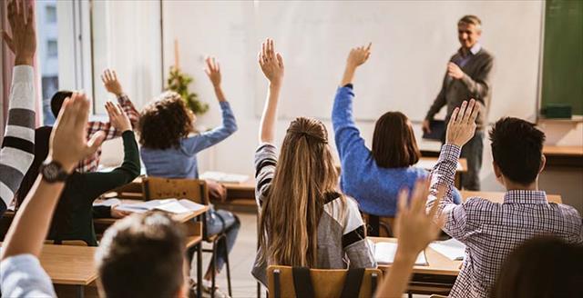 Kids raising their hands in a classroom