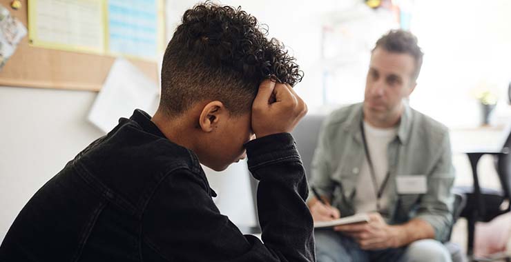 Mental health specialist attentively takes notes while sitting across from a young child