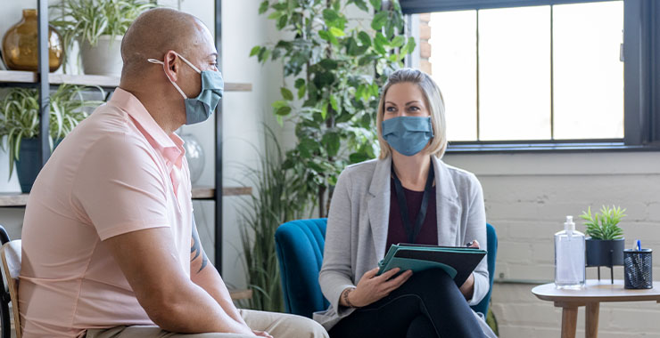 two people in a therapy setting, both wearing masks