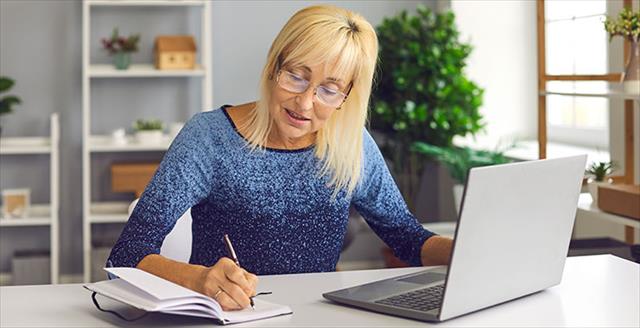 woman taking notes in front of laptop