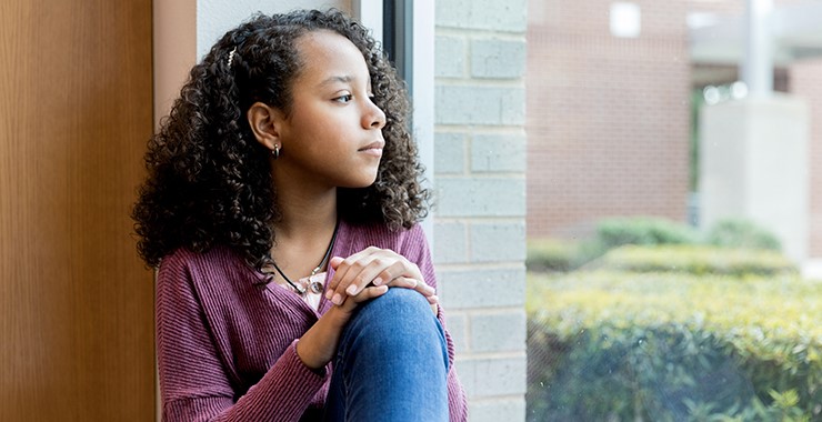 young woman of color looking out a window