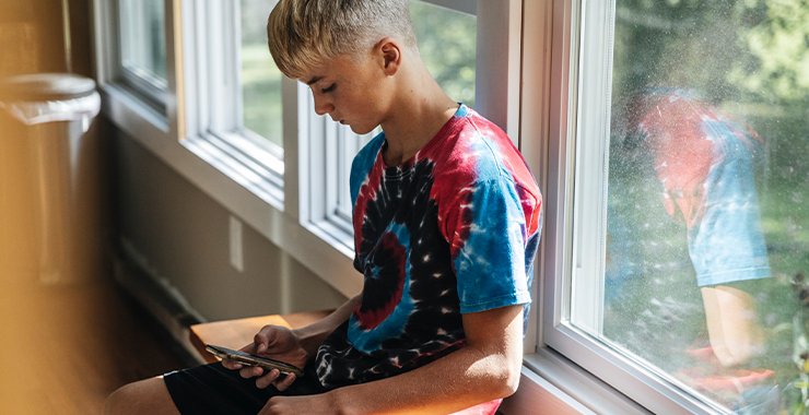 teenage boy looking on his phone in a classroom