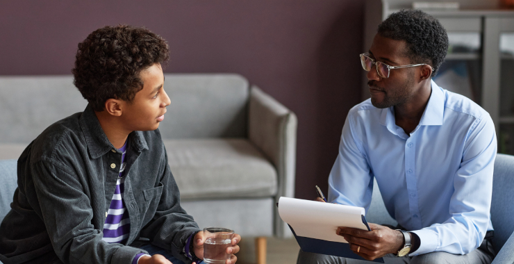 Teenage boy drinking water when talking to adolescent psychologist about his worries and problems