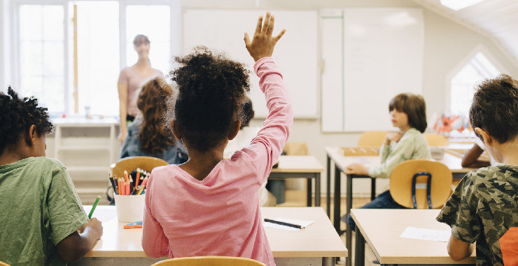 child raising hand in classroom