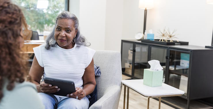 The serious senior adult therapist uses her digital tablet to document the unrecognizable woman's comments
