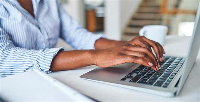 A pair of woman's hands typing on computer keyboard