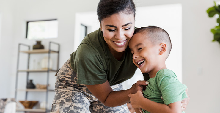 woman wearing military fatigues tickling a young boy