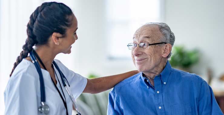 A doctor and senior patient smiling at each other in a medical office