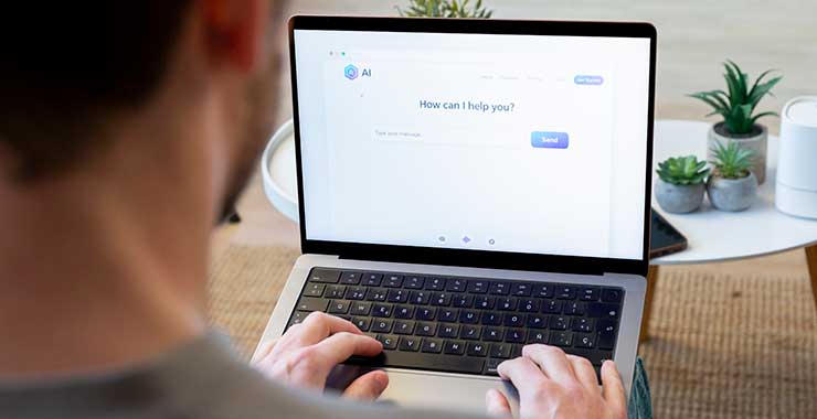A man types on a laptop displaying a generative AI interface at his desk.