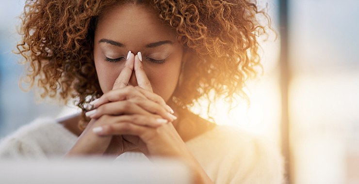 A woman with her eyes closed who appears overwhelmed