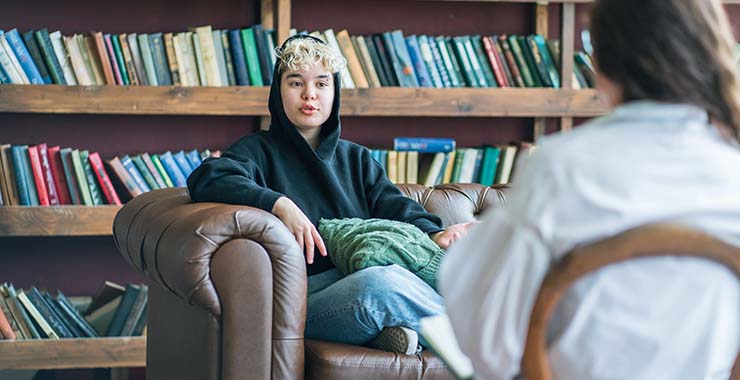 A teenager sitting with a behavioral health specialist