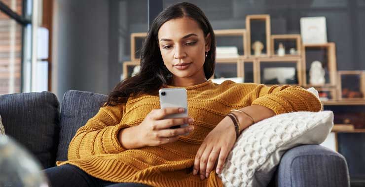 A woman sitting on a couch looking at her smartphone