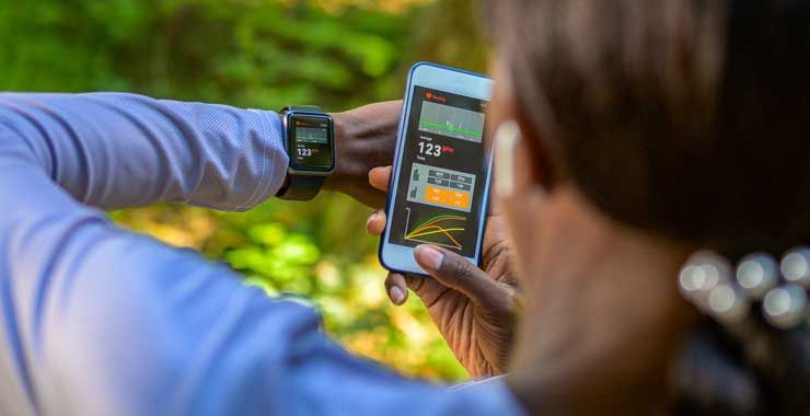 Woman on a nature trail using her smartphone and smartwatch to monitor her vital signs