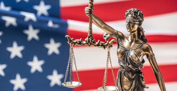 statue of blind justice in front of American flag