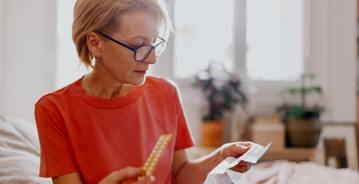 a middle-aged woman reading information on prescription medicine